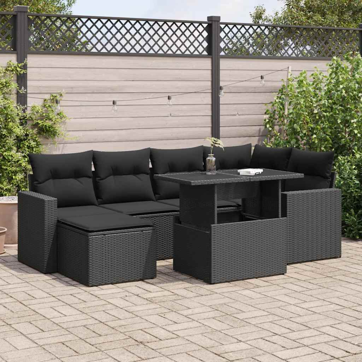 Set di mobili da esterno in vimini nero con tavolo, divano e pouf su un patio.