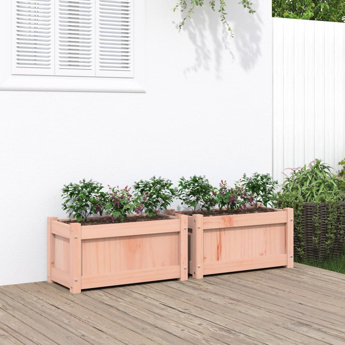 Zwei Holzpflanzkästen mit grünen Pflanzen stehen auf einer Holzterrasse.
