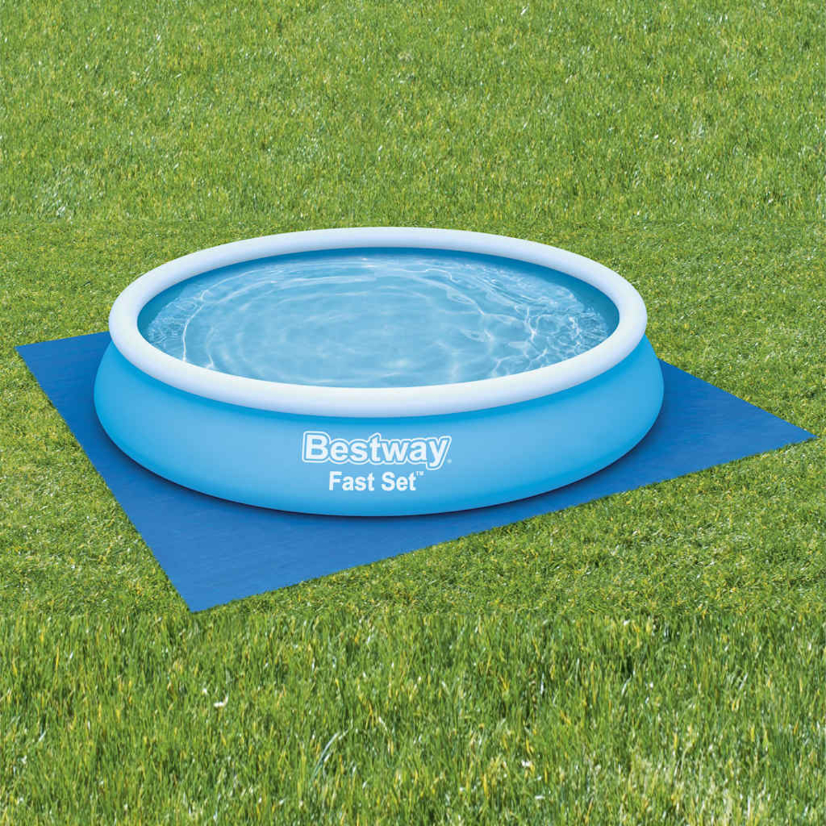 Ein blaues aufblasbares Schwimmbecken auf einer blauen Matte auf grünem Gras.
