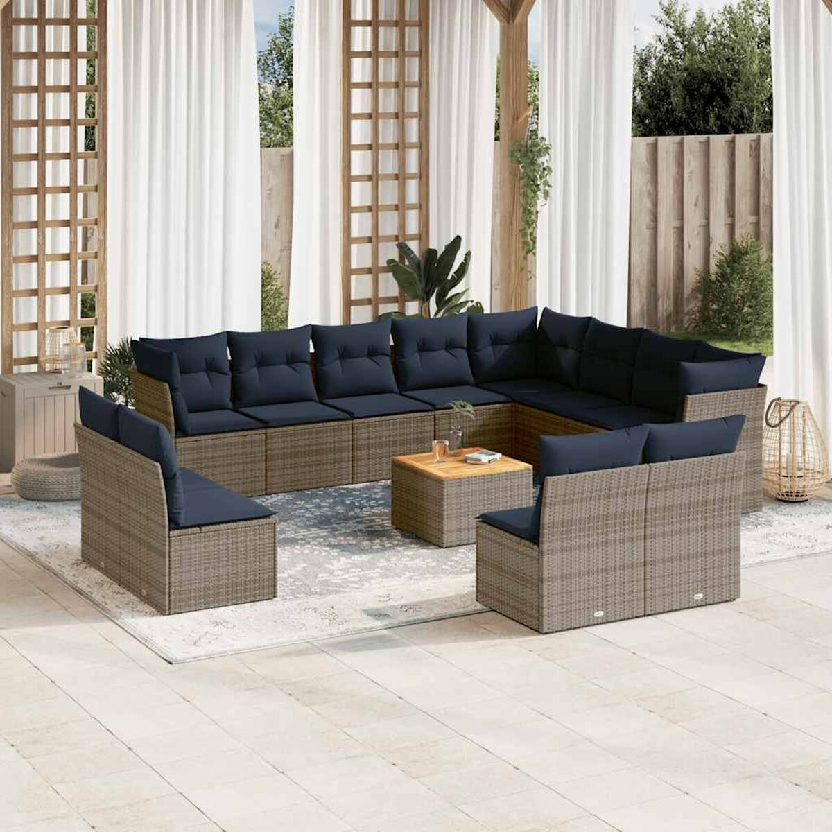 Un divano componibile in rattan da esterno con cuscini blu, un tavolino in legno, su un tappeto fantasia.