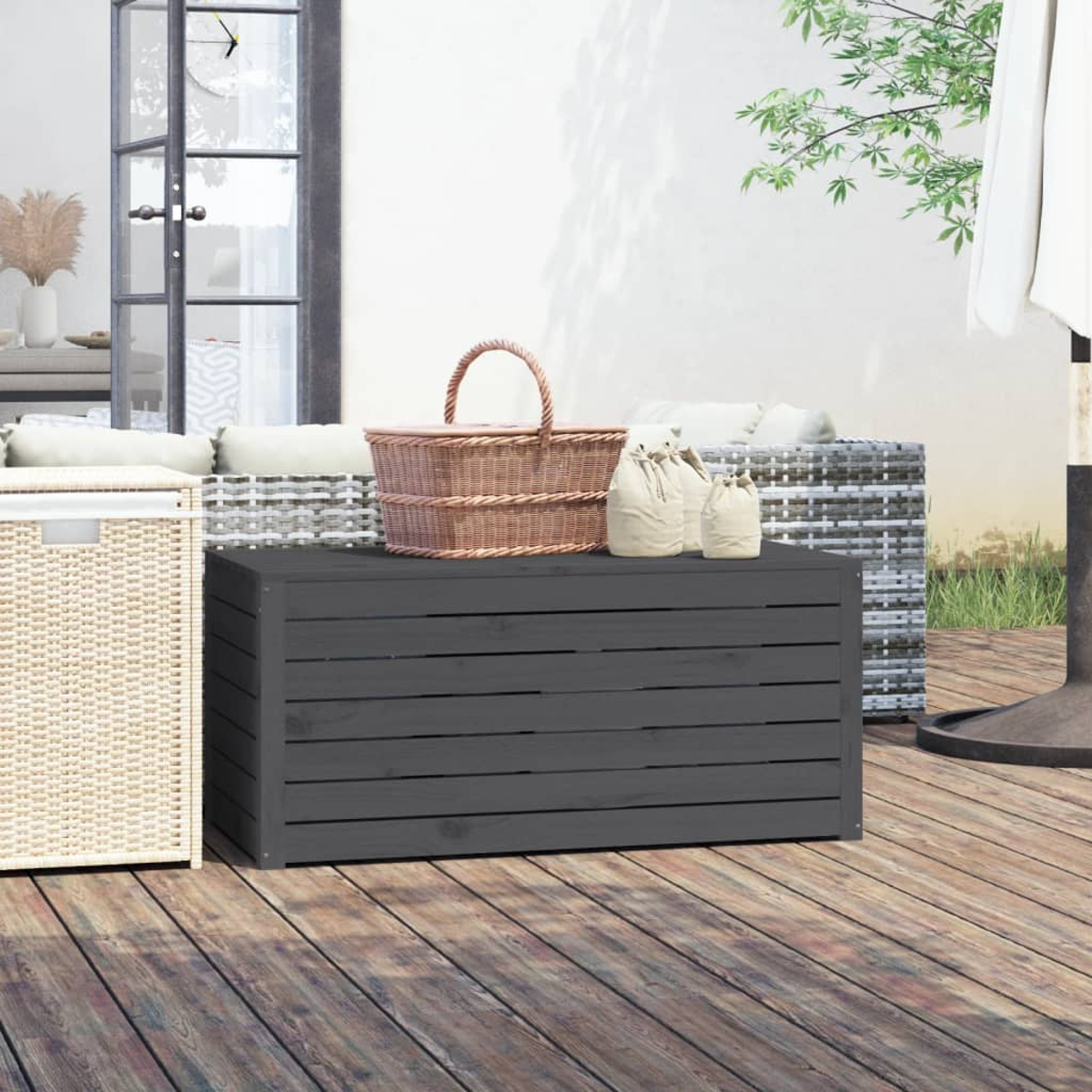 Eine hölzerne Aufbewahrungsbox für den Außenbereich auf einem Holzdeck mit einem Weidenkorb und Taschen oben.
