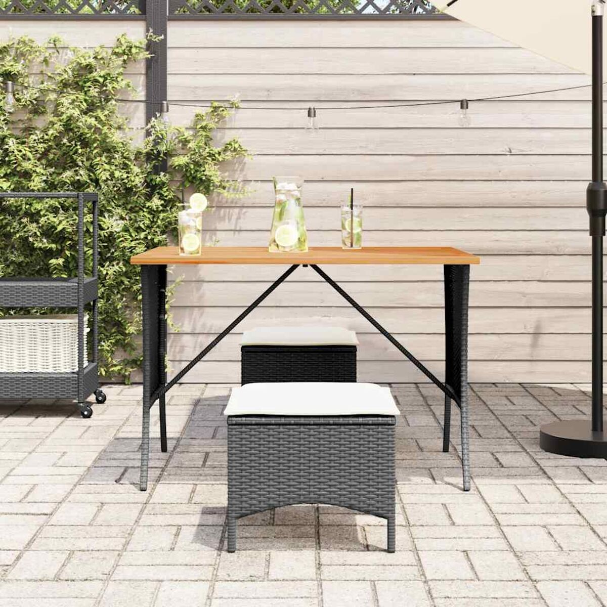 Garten-Set mit Getränken und Hockern. Hintergrund sind Pflanzen, ein Zaun und eine Wand.