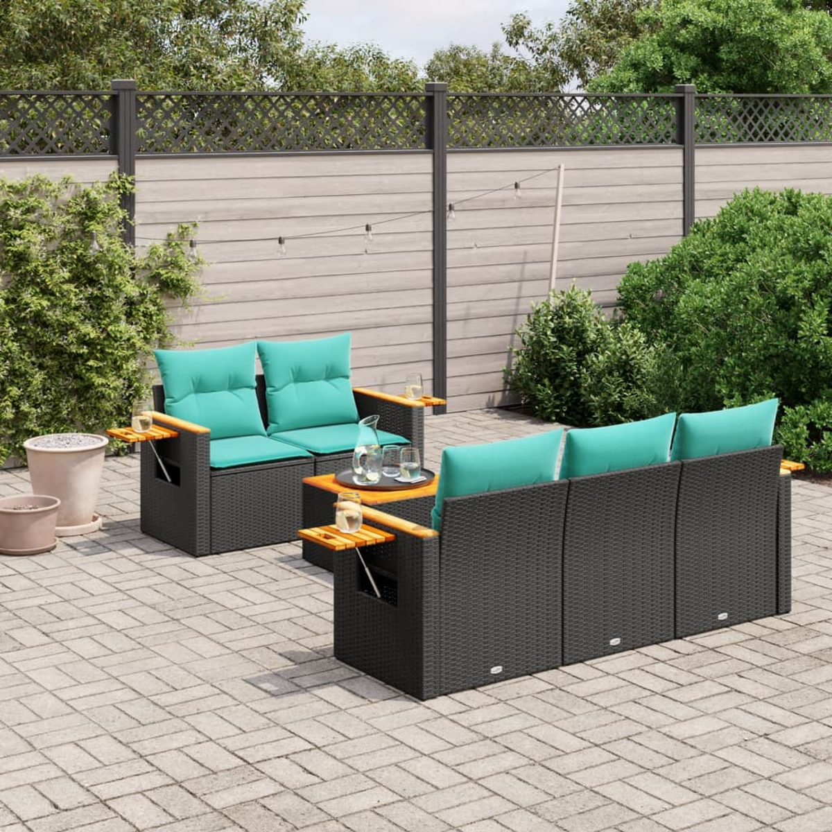 Set divano in rattan da esterno con cuscini verde acqua, un tavolo e un patio in mattoni.