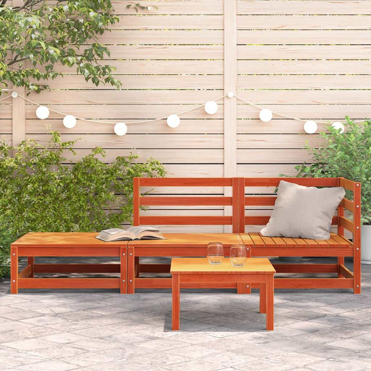 Gartenmöbel-Set aus Holz mit Sofa und zwei Couchtischen. Lichterketten hängen darüber.