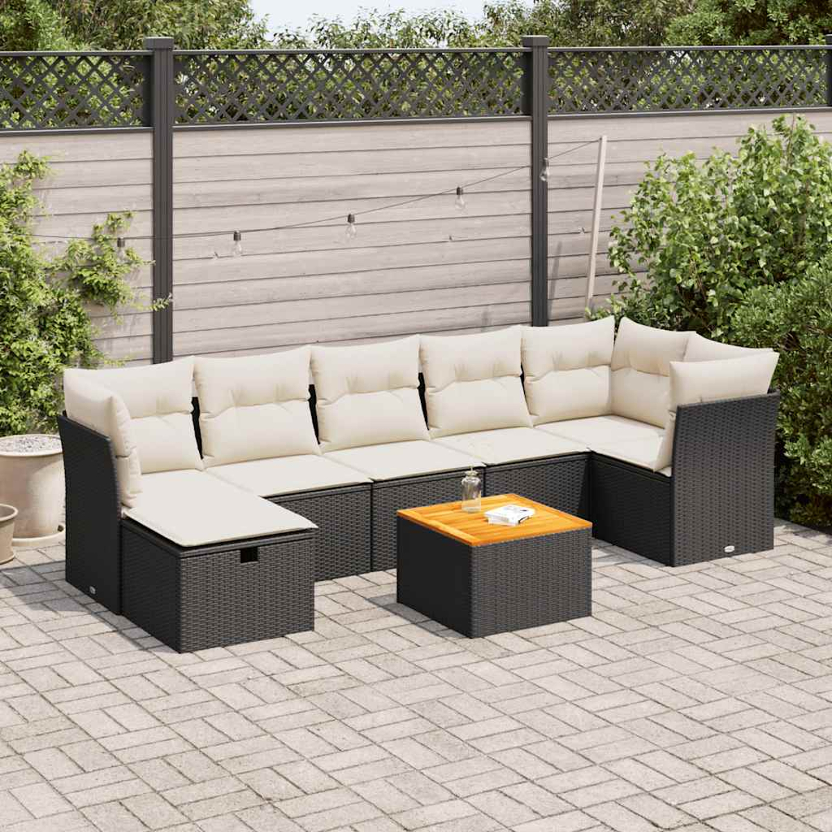 Set divani in vimini neri con cuscini beige, tavolino, patio in mattoni.