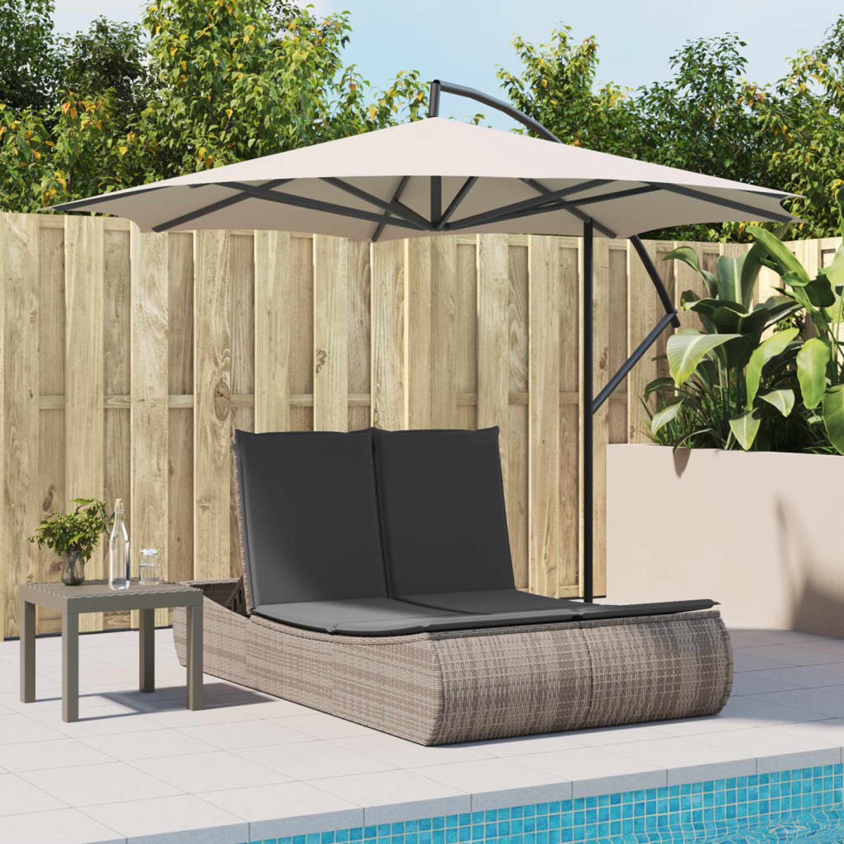 Szene im Freien mit einem grauen Tisch, zwei Sonnenliegen und einem Sonnenschirm. Pool und Grün im Hintergrund.