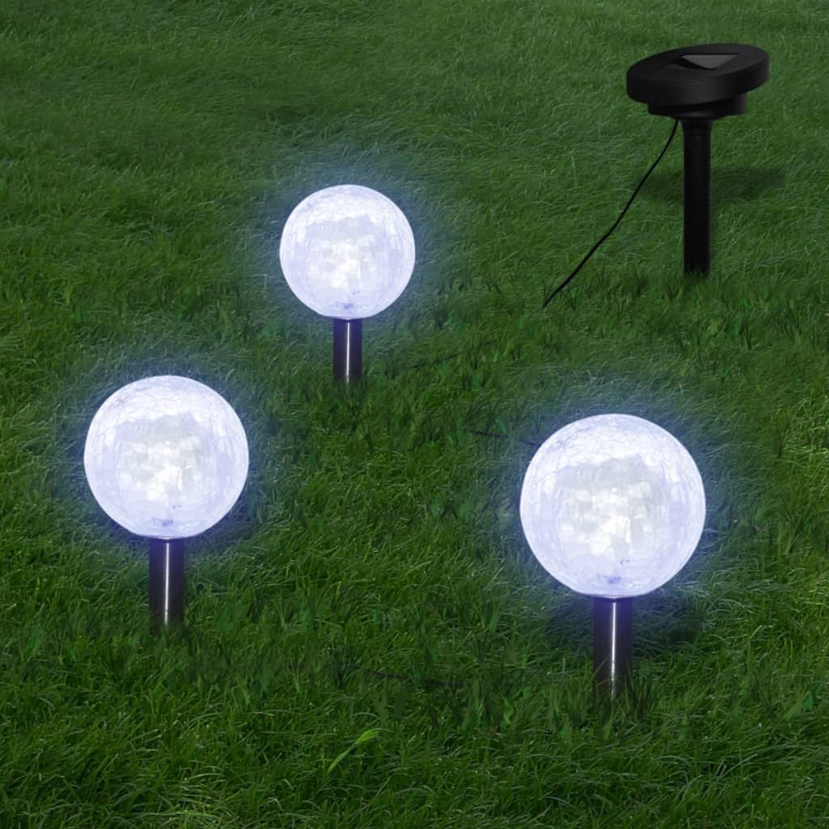 Drei Solar-Gartenleuchten mit weißen Kugeln auf grünem Gras. Ein Solarpanel ist ebenfalls sichtbar.