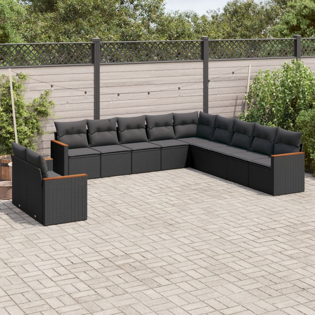 Ein schwarzes Ecksofa mit dunkelgrauen Kissen und Holzarmlehnen auf einer Terrasse.