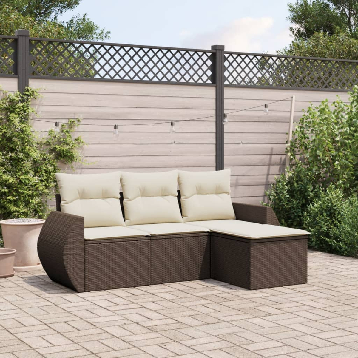 Divano da esterno in rattan marrone con cuscini color crema. Ambientazione patio, scena soleggiata.