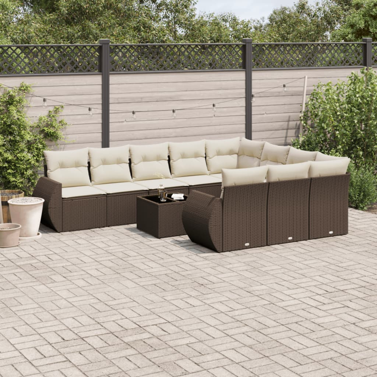 Set da patio in rattan marrone con cuscini beige su un patio pavimentato.