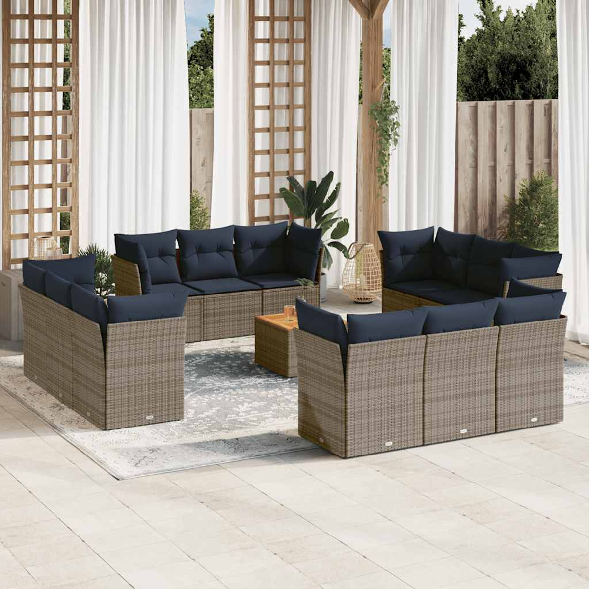 Un ampio set di divani in rattan da esterno con cuscini blu scuro e un tappeto chiaro, sotto un pergolato.