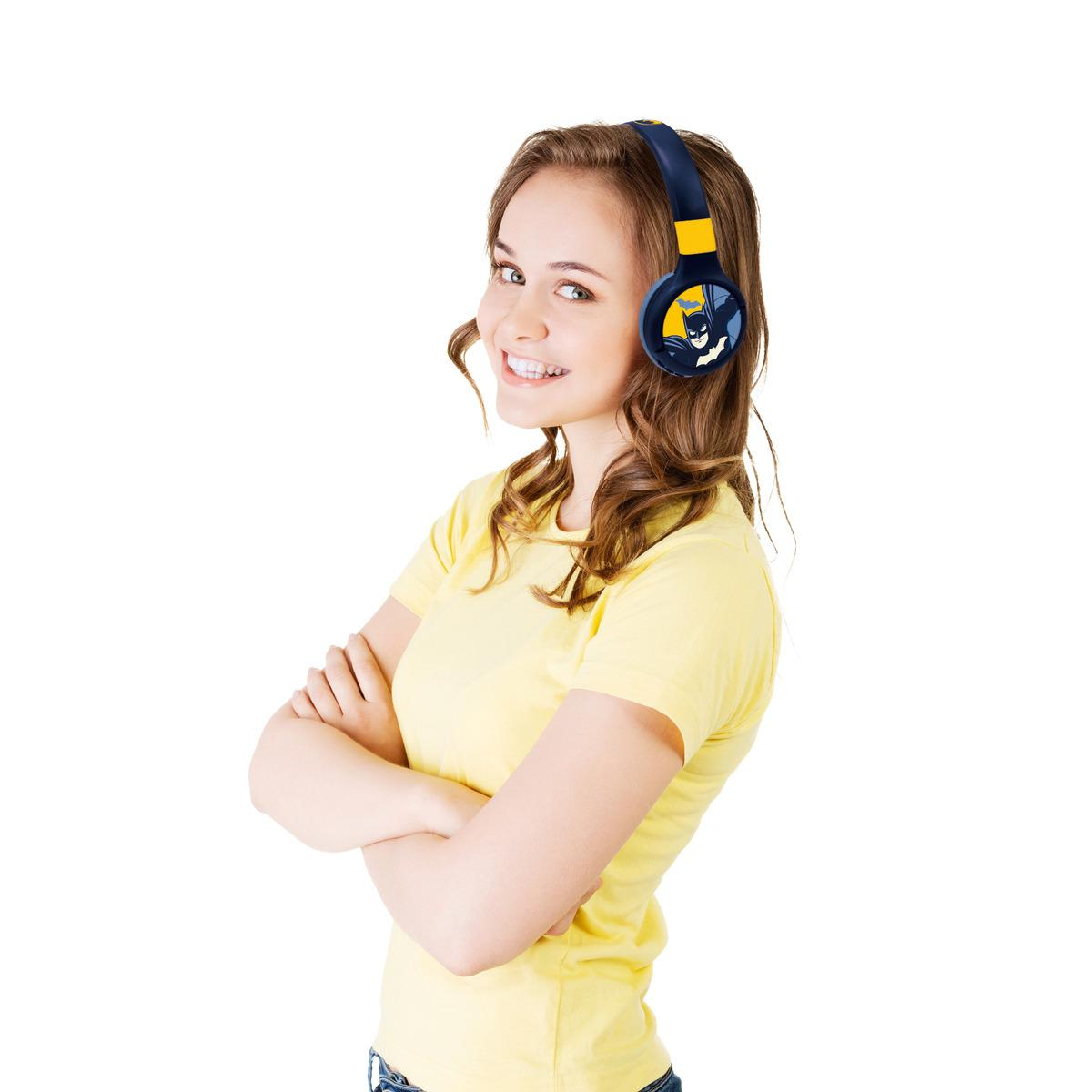 Una donna sorridente con cuffie Batman. Ha i capelli castani e indossa una maglietta gialla. Sfondo bianco.
