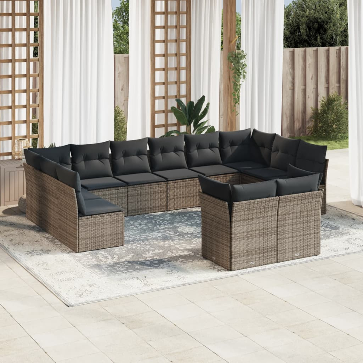 Ein Outdoor-Ecksofa aus Korbgeflecht mit schwarzen Kissen auf einem grauen Teppich. Vorhänge und Zaun.