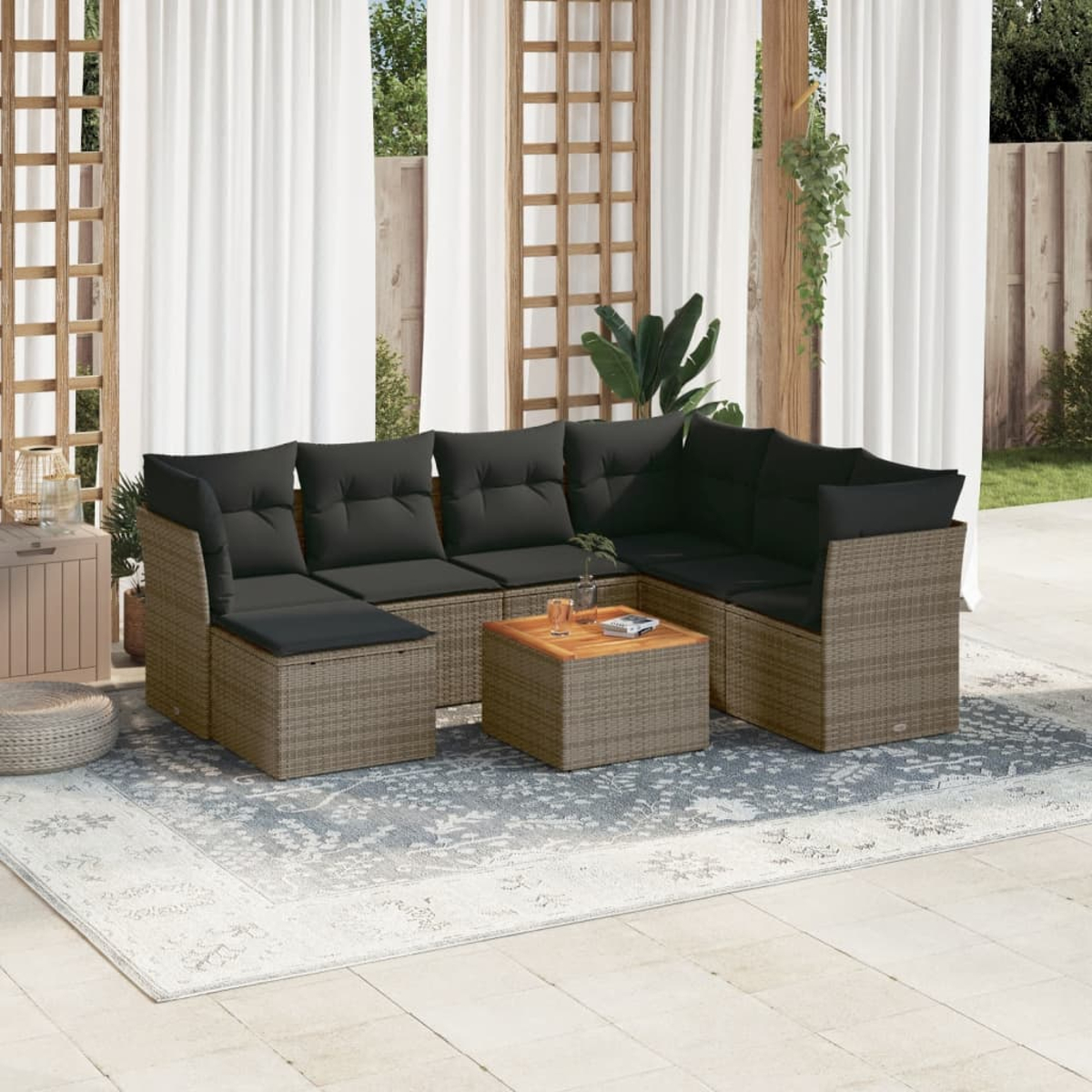 Braunes Wicker-Outdoor-Sitzgruppe mit dunkelgrauen Kissen, kleinem Tisch und gemustertem Teppich, Patio im Hintergrund.