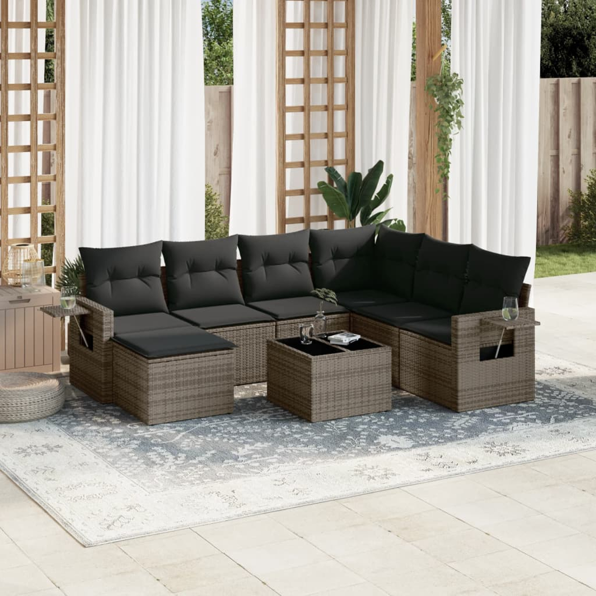 Geflochtenes Outdoor-Sofaset mit grauen Kissen, Tisch und Teppich.