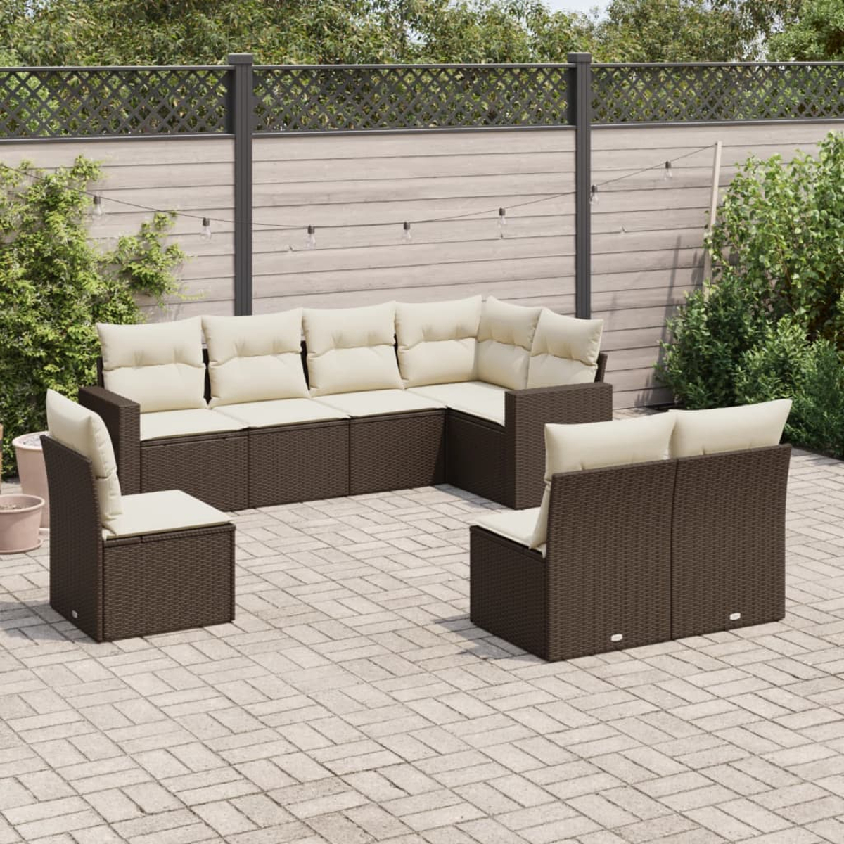 Ein Rattan-Terrassenset mit cremefarbenen Kissen, angeordnet auf einer Ziegelterrasse.