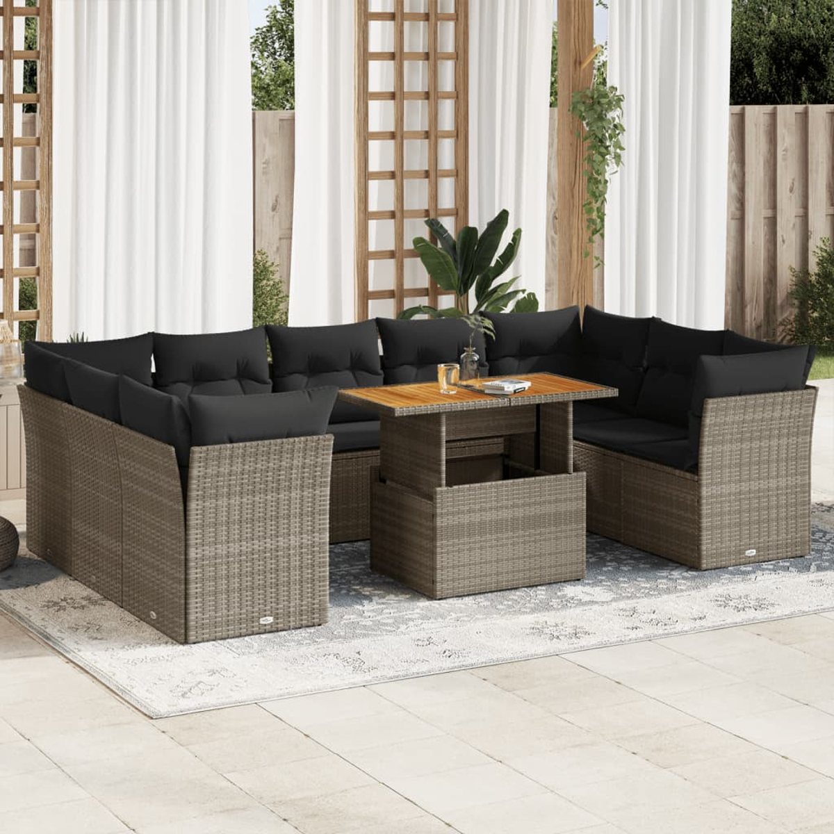 Set da patio esterno con divano, tavolo e cuscini. Vimini grigio con cuscini neri, su un tappeto.