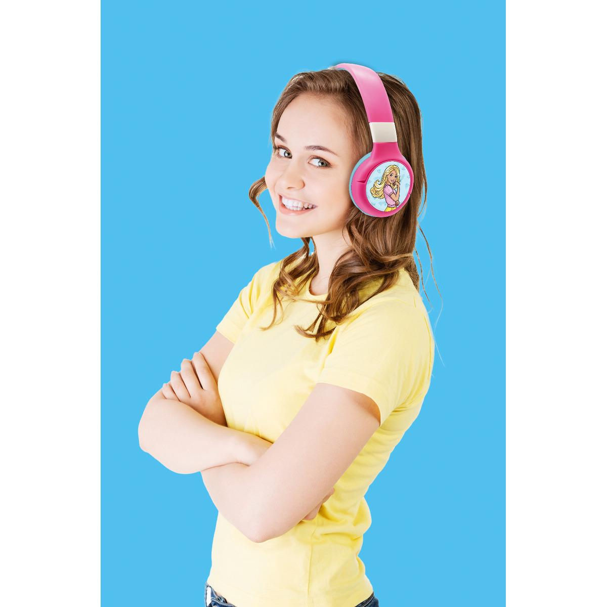 Una niña sonriendo con auriculares Barbie rosas sobre un fondo azul.