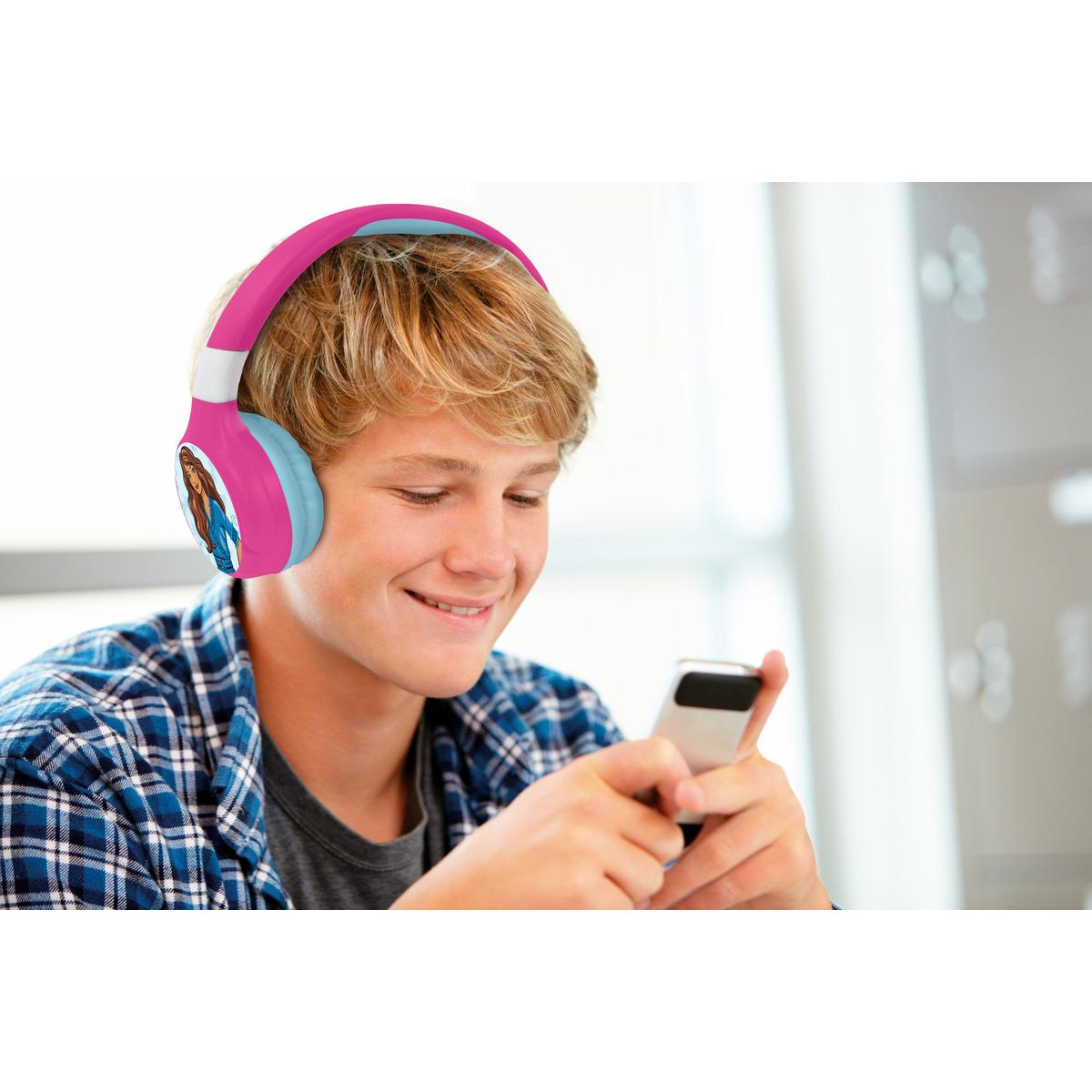 Adolescente usando un teléfono, con auriculares, sonriendo.