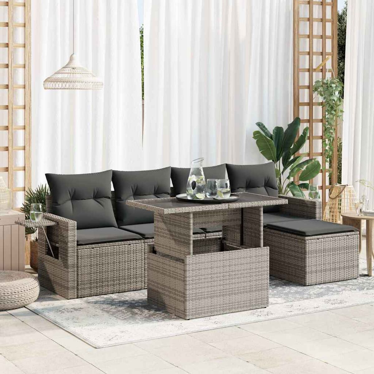 Geflochtenes Outdoor-Sofa mit dunkelgrauen Kissen, einem Tisch mit Hebefunktion und einem Teppich.