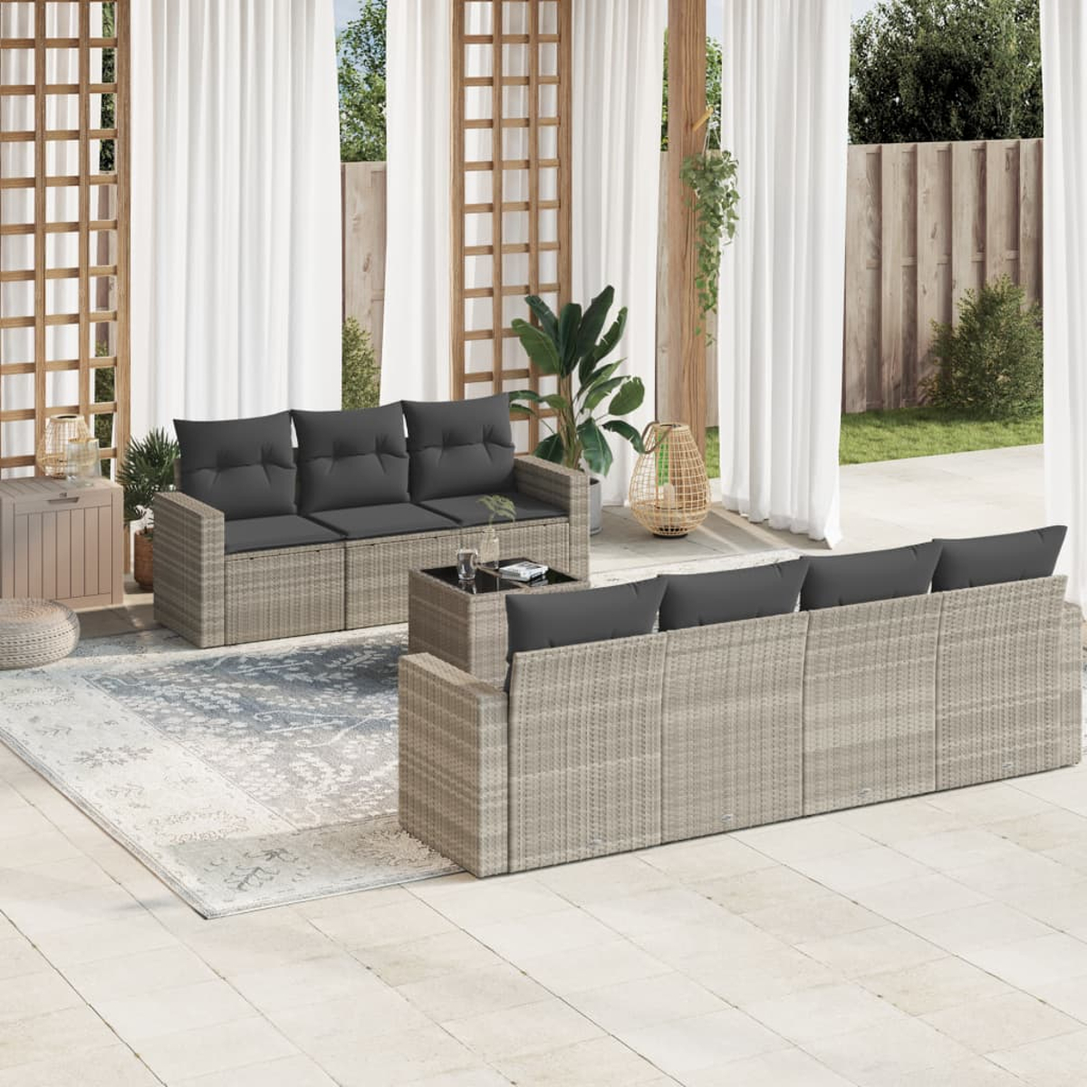 Mobili da patio in rattan beige. Divano a L, tavolino. Ambientazione in cortile, tende bianche.