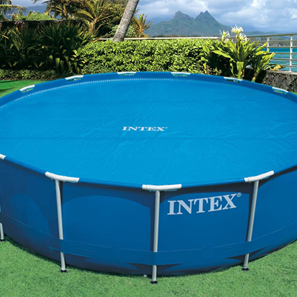 Piscina Intex blu, rotonda, con copertura. Erba verde e vista sull'oceano e le montagne sullo sfondo.