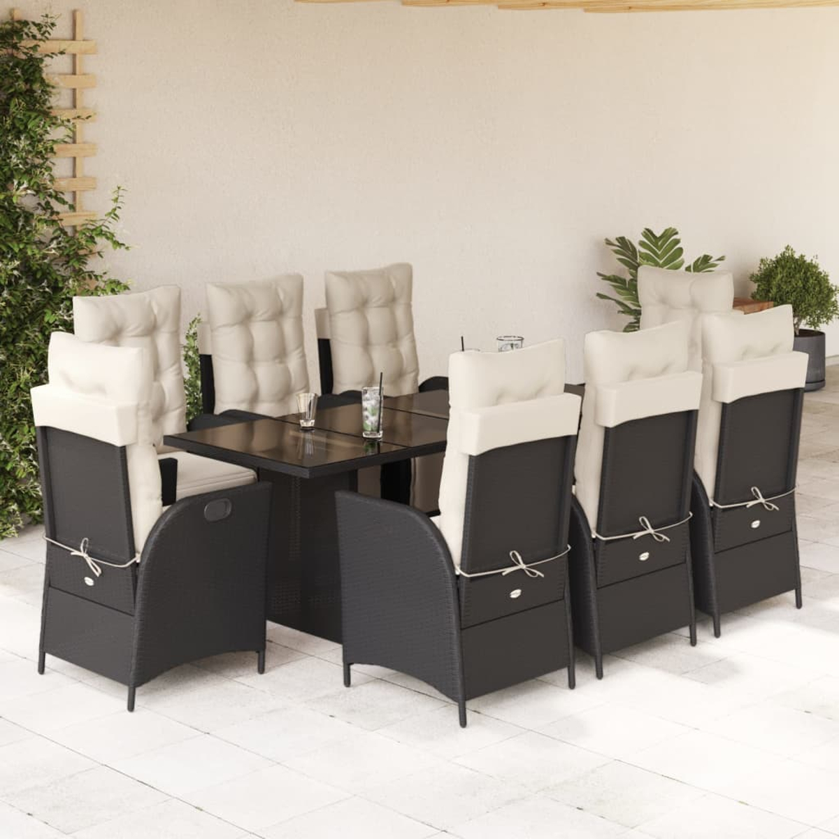 Outdoor-Essgruppe. Schwarze Korbstühle mit weißen Kissen, Tisch. Hintergrund: Terrasse, Pflanzen.