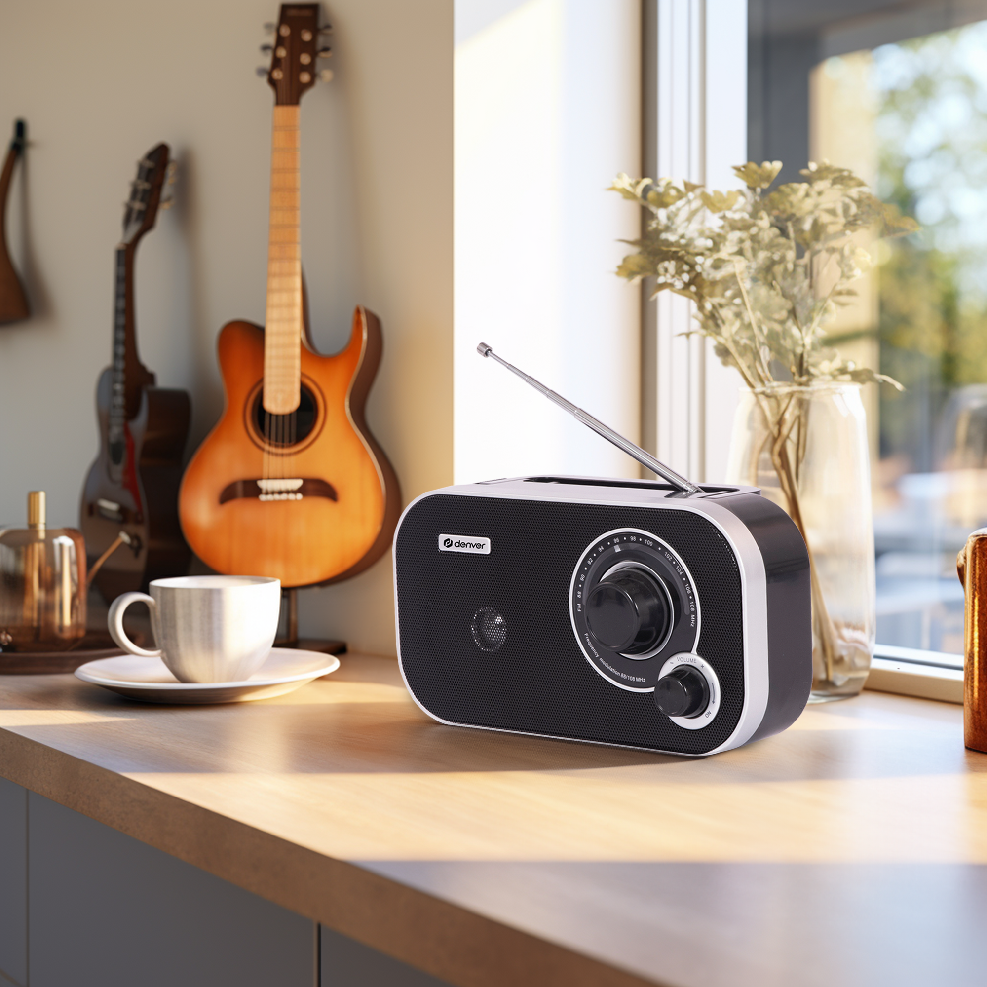 Radio na drewnianej powierzchni z filiżanką, gitarami i kwiatami w tle.