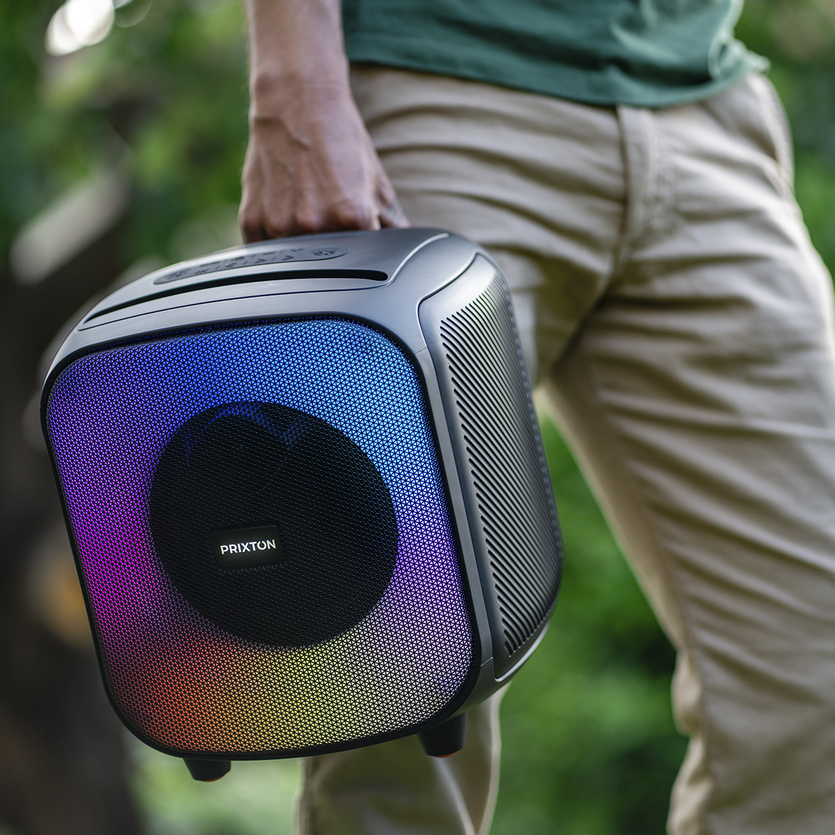 Osoba trzyma czarny i kolorowy głośnik. Tęczowe światła z przodu.