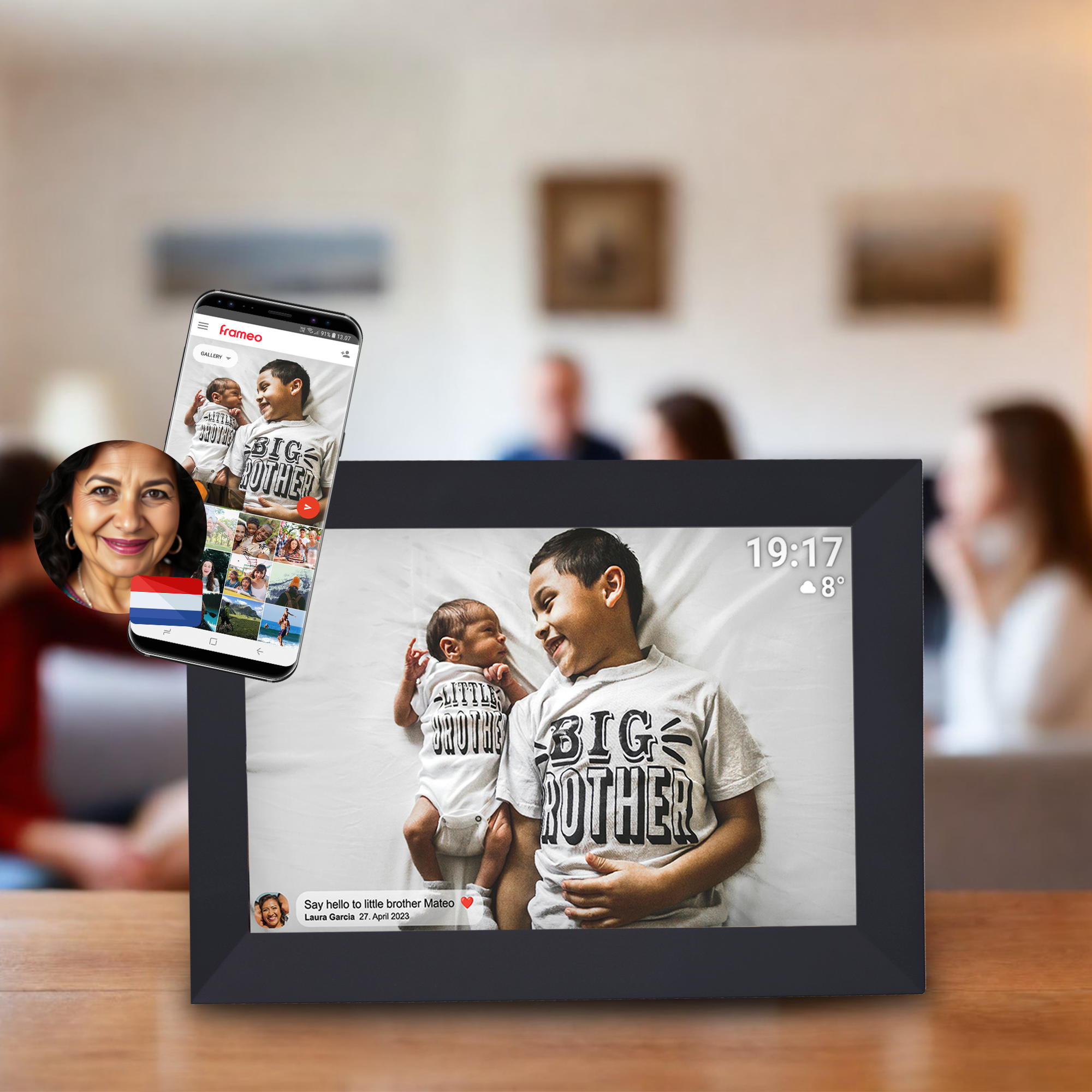 Un cadre photo numérique affiche un bébé et un bambin. Un téléphone affiche la même photo. Une femme est dans le coin de l'écran.