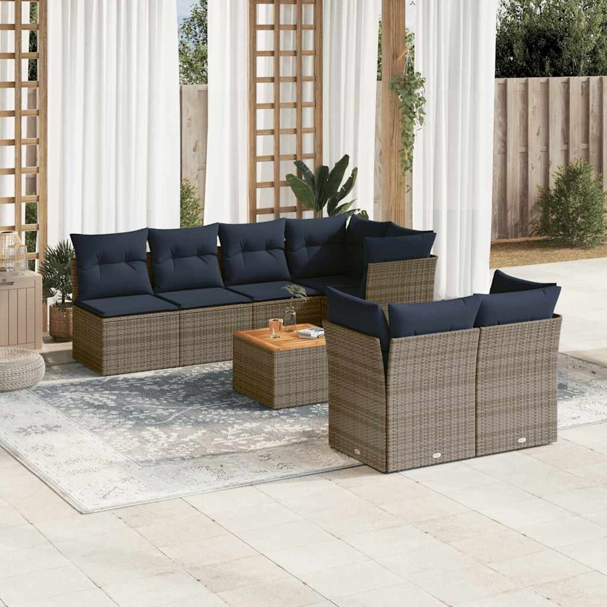 Ecksofa im Freien mit marineblauen Kissen auf einer Terrasse mit einem gemusterten Teppich und einem Holztisch.