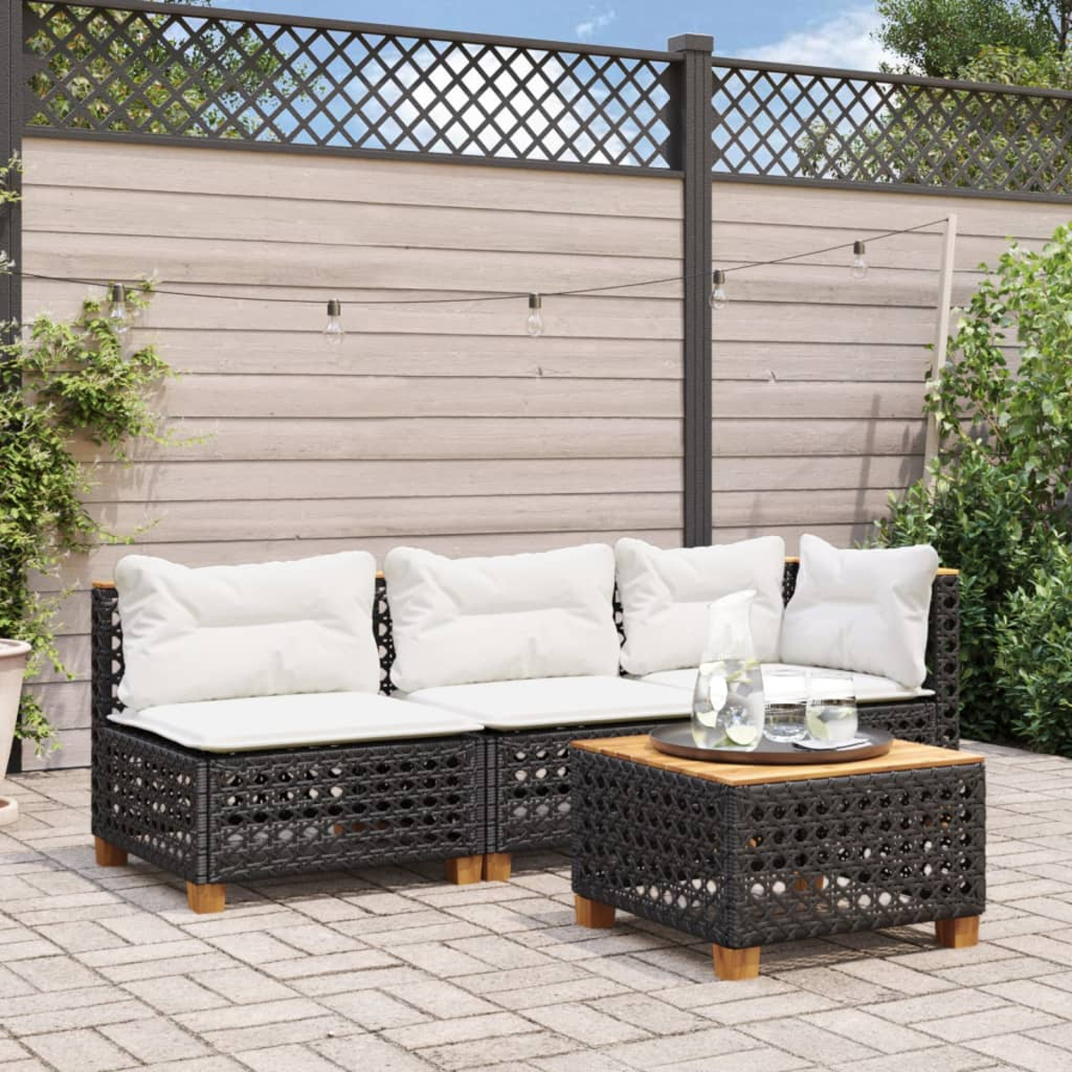 Outdoor-Sitzgruppe mit Sofa und quadratischem Tisch. Weiße Kissen, dunkle gewebte Rahmen und Pflanzen sind vorhanden.