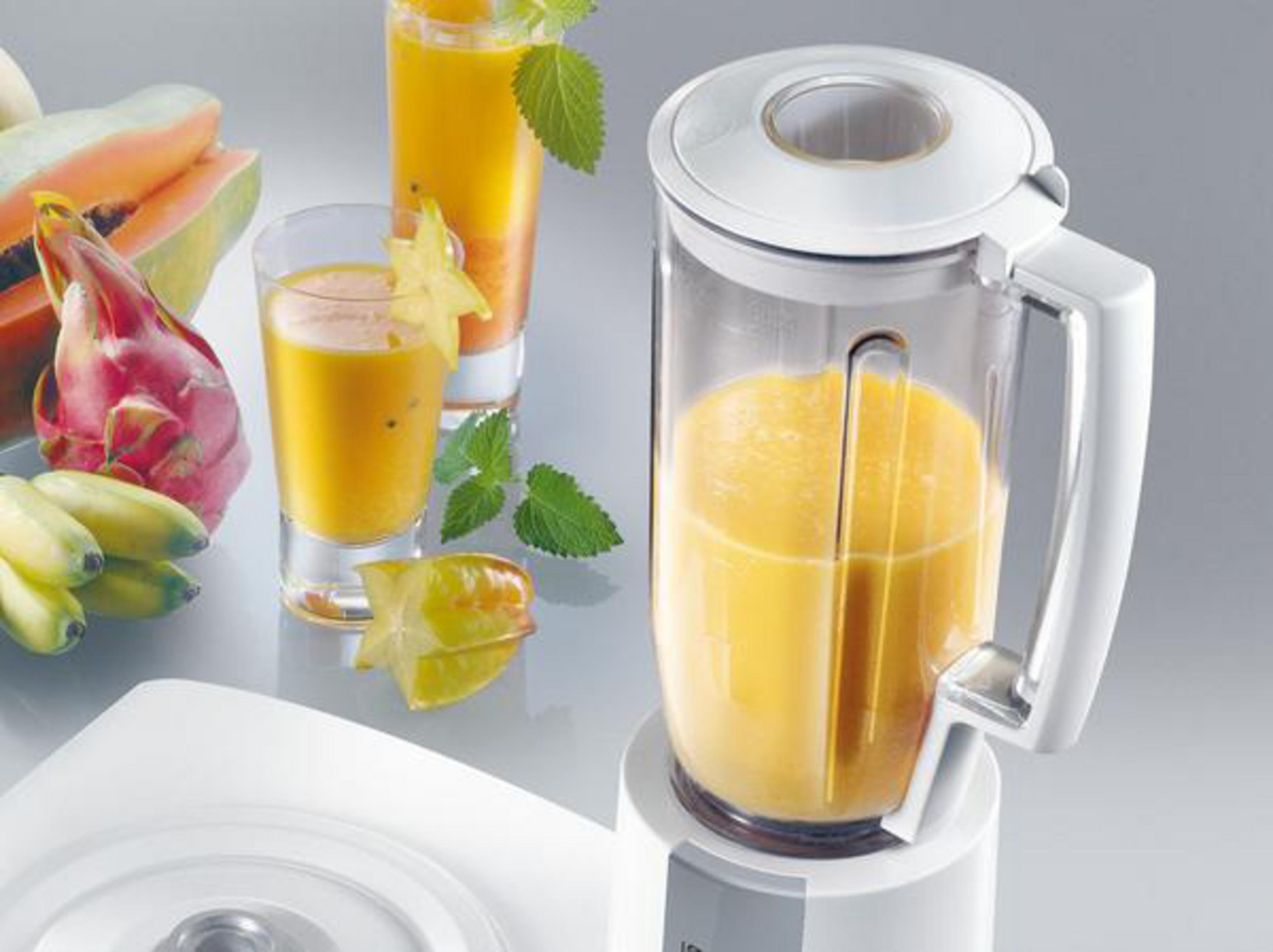 Blender met sinaasappelsmoothie en fruit: stervrucht, papaja en bananen.