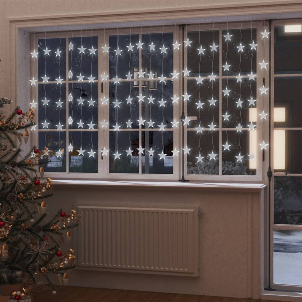 Fenster mit sternförmigen Lichtern. Ein Weihnachtsbaum links, Schnee draußen.