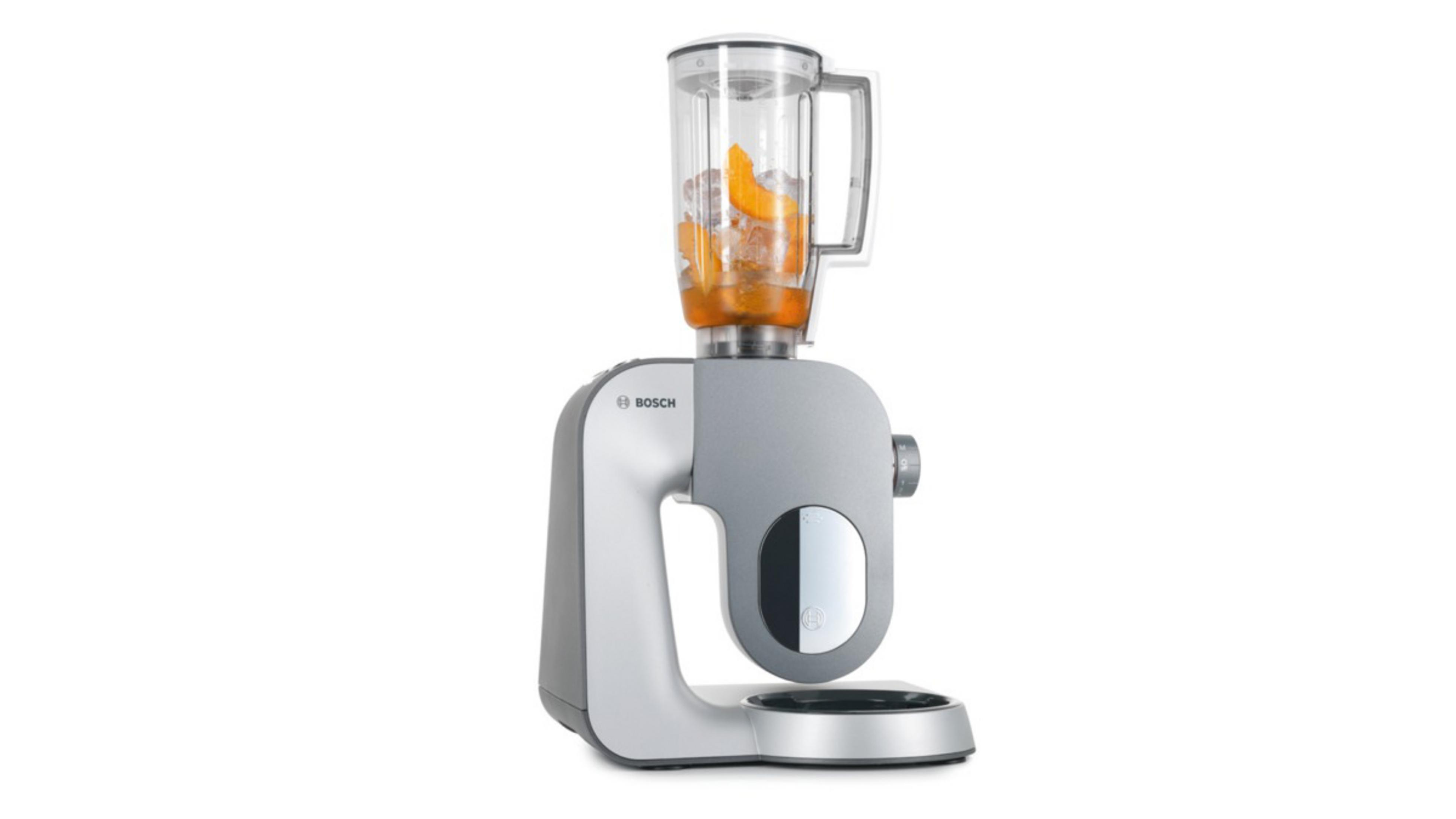 Ein silberner und grauer Foodprozessor mit einem transparenten Mixer, der mit Orangenscheiben gefüllt ist.