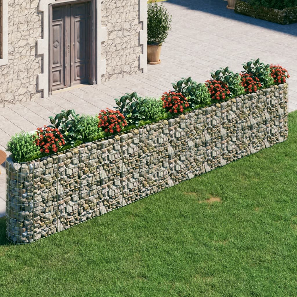 Ein Steinpflanzer mit Pflanzen gefüllt. Der Pflanzer steht auf Gras, neben einem Haus.