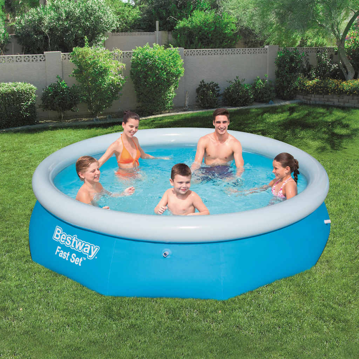Eine fünfköpfige Familie in einem blauen aufblasbaren Pool auf einer grünen Wiese.