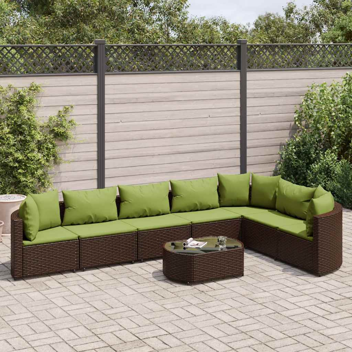 Sofá seccional exterior con cojines verdes y mesa de centro. Muebles de mimbre marrón en un patio.