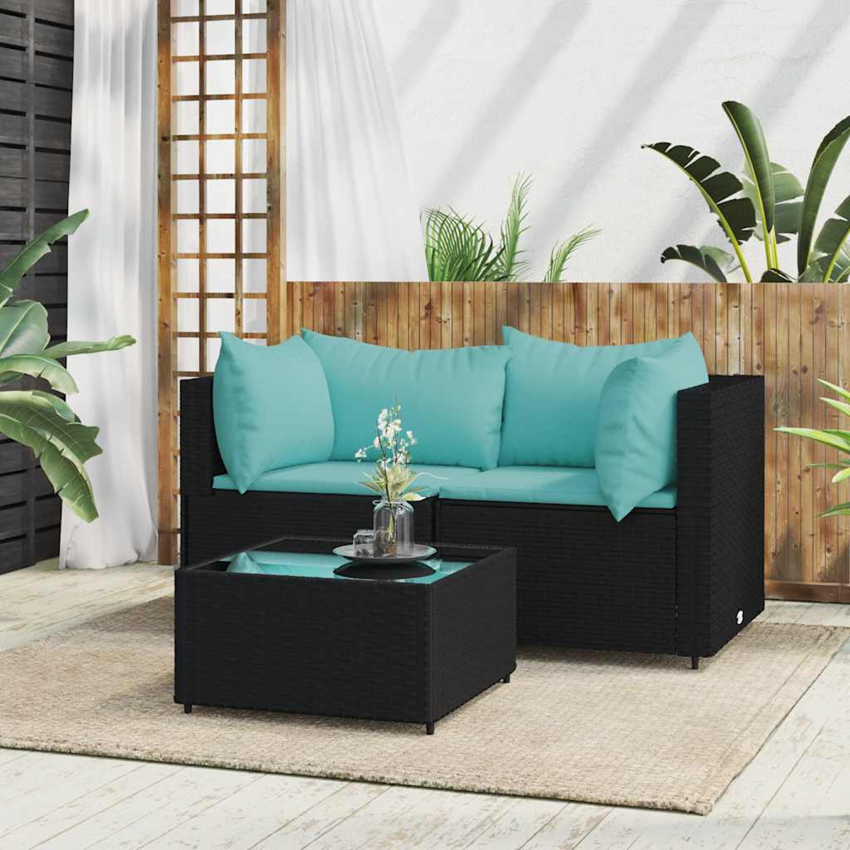Schwarzes Outdoor-Korbs sofa mit türkisfarbenen Kissen und einem passenden Tisch. Die Szene ist im Freien.
