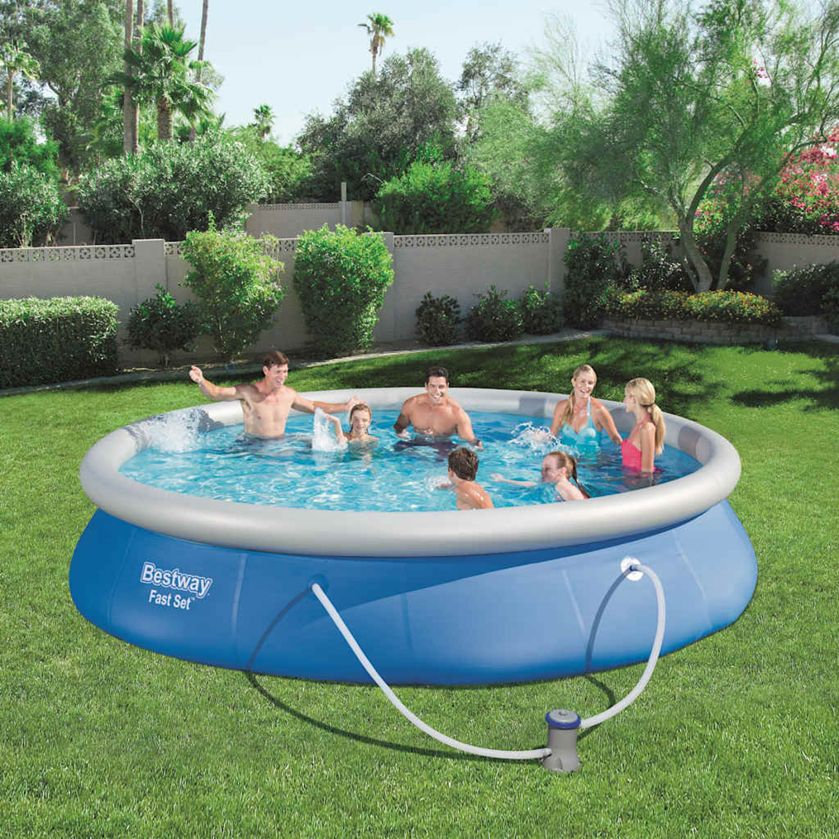 Menschen in einem blauen Pool. Der Pool befindet sich in einem grünen Garten. Blaues Wasser und blaue Poolwände.