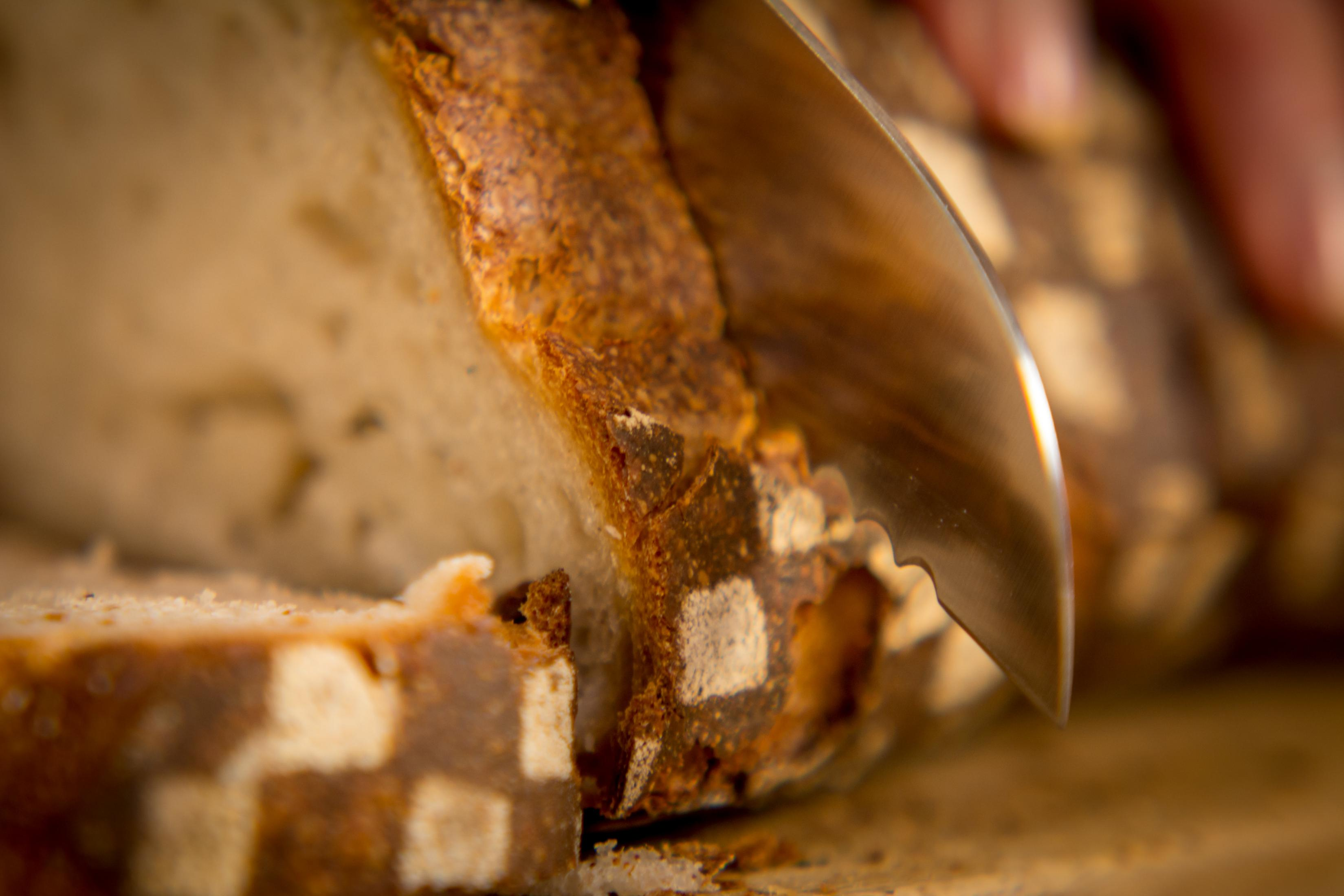 Chleb krojony nożem z ząbkowanym ostrzem, ujęcie z bliska.