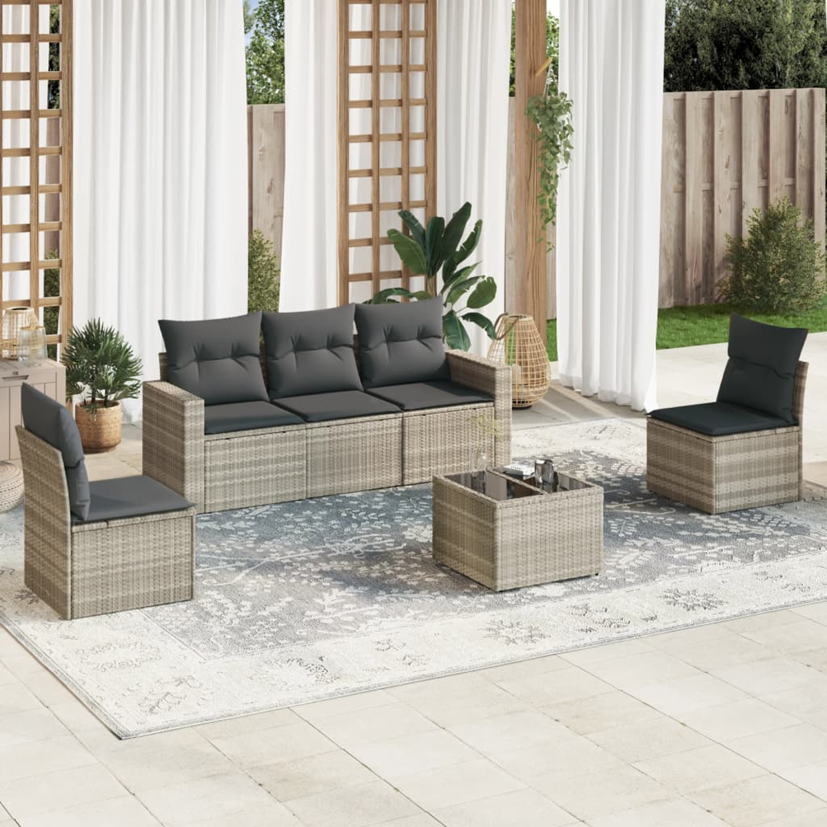 Set di mobili per patio all'aperto con divano, due sedie e tavolino su un tappeto fantasia.