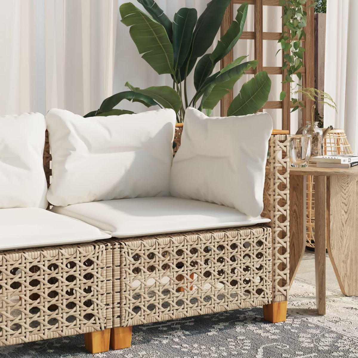 Primo piano di un divano in rattan con cuscini bianchi. Un tavolino in legno a destra.
