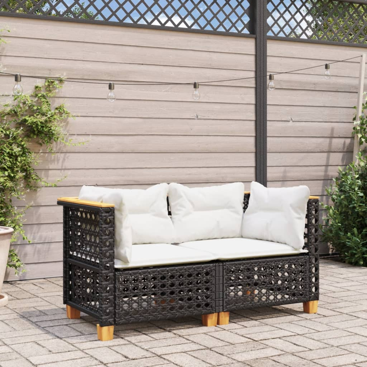 Schwarzes Rattan-Zweisitzer-Sofa mit weißen Kissen und Holzbeinen.