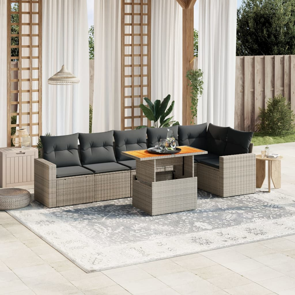 Außenbereich mit grauen Sofas, einem Holztisch und einem gemusterten Teppich. Vorhänge im Hintergrund.