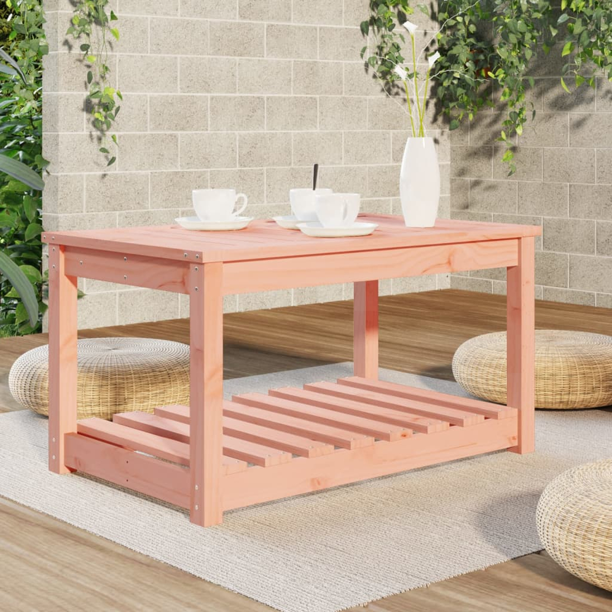 Ein rosa Holztisch mit Lattenregal, auf einem Teppich, mit Vase und Tassen.
