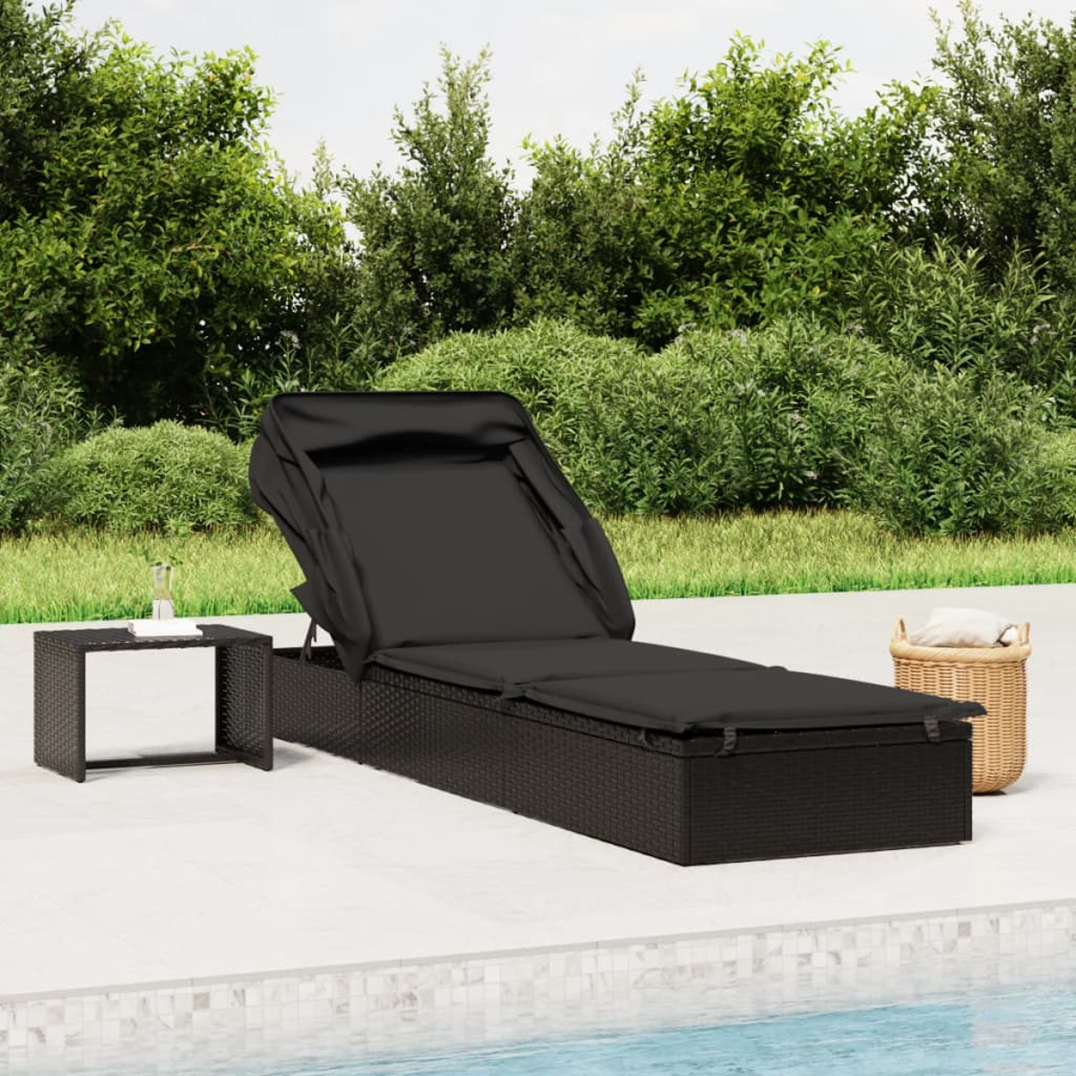 Schwarze Korbliege mit schwarzem Kissen und einem kleinen Tisch daneben, in der Nähe eines Pools.