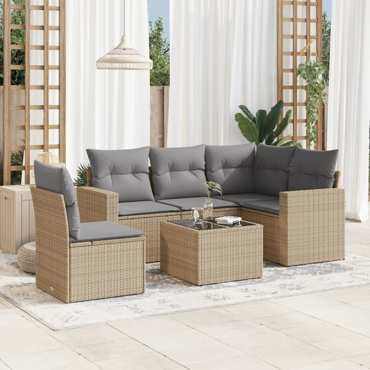 Rattan-Sitzgruppe für den Außenbereich mit Tisch, Kissen und Dekor auf einer Terrasse.