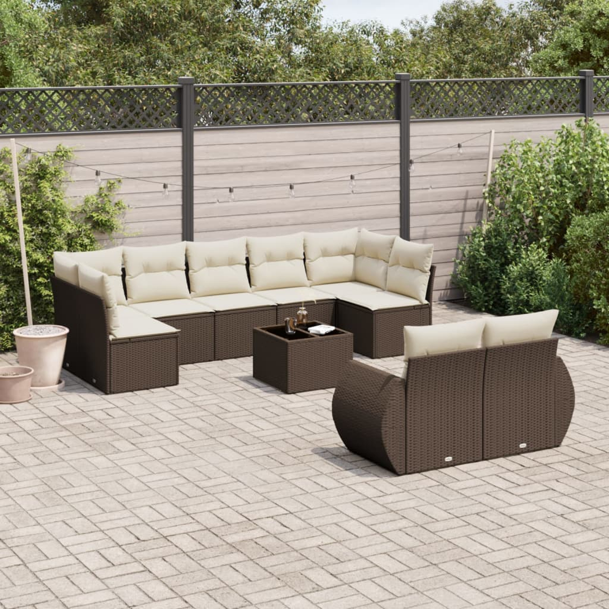 Set divano componibile in vimini marrone da esterno con cuscini beige e tavolo quadrato su un patio pavimentato.