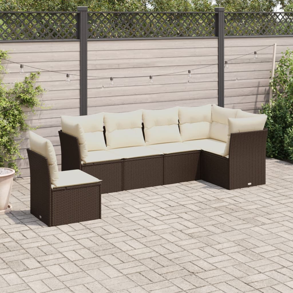 Divano a L in rattan con cuscini color crema e una sedia abbinata, su un patio in mattoni.